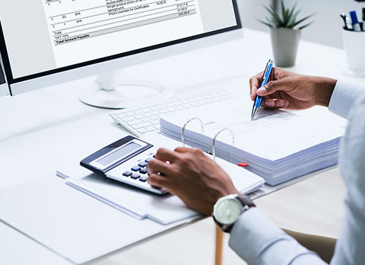 Person using calculator at desk in dealership. 