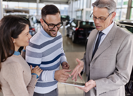Dealership customers looking over deal paperwork on tablet