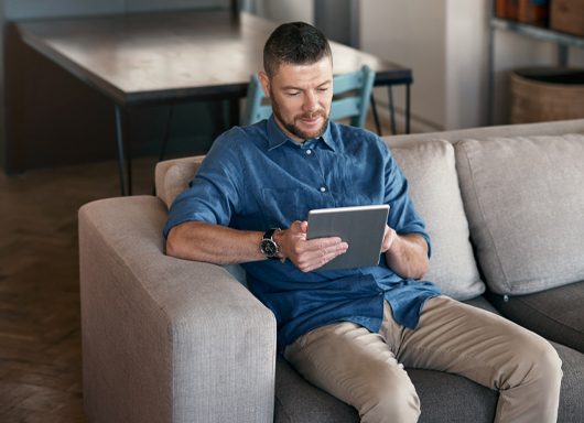 Man sitting on couch shopping on tablet using Gubagoo Virtual Retailing 
