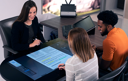 Photo of a couple sitting at a docuPAD system desk with f&i manager