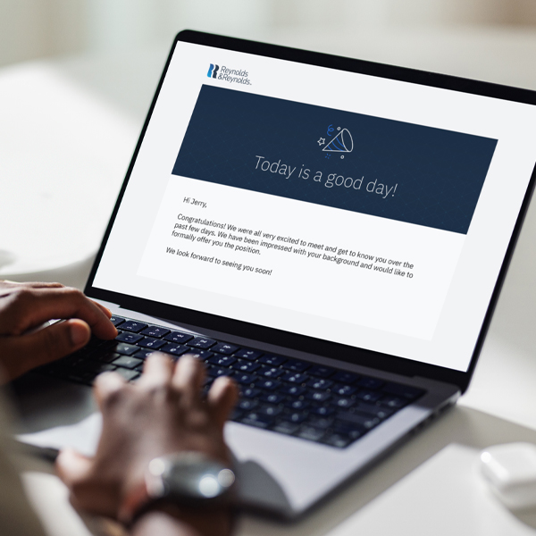 Young man looking at laptop screen with job offer email from Reynolds.