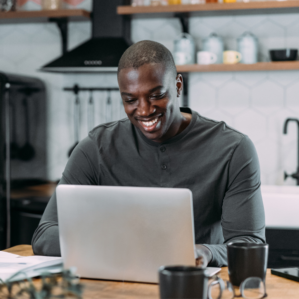 Young man in his kitchen looking at this laptop, applying for a job at Reynolds.