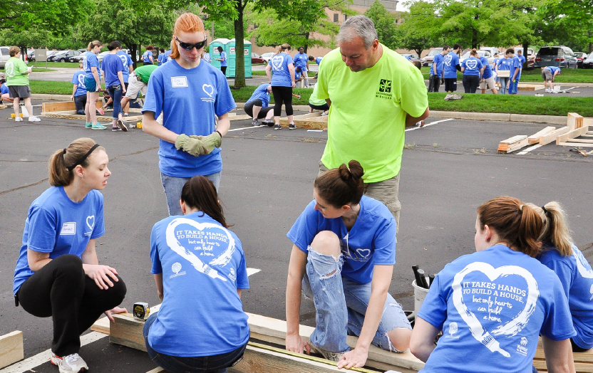 Group of people with Habitat for Humanity shirts on building a wall for the Habitat house.