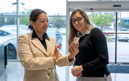Two women looking at phone inside dealership